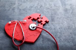67551613 - red puzzle heart with stethoscope on grey wooden background